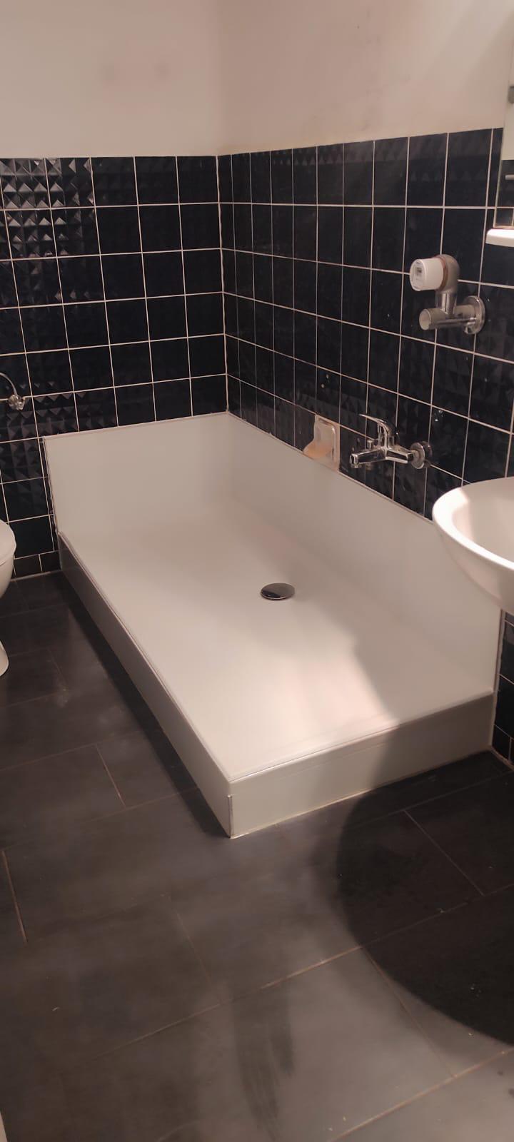 Badewanne vor dem Umbau in einem Badezimmer mit dunklen Fliesen